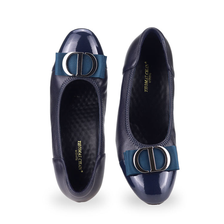 Front view of Thomas Chan cream-colored ribbon buckle court shoes, featuring patent blue detail at the toe cover.