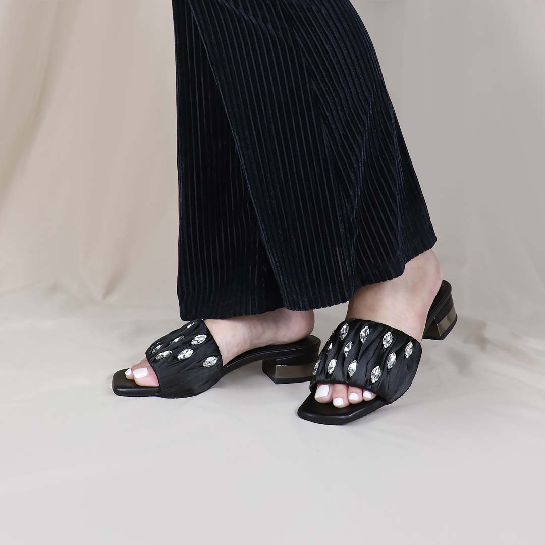 Model wearing Crystal Lux Satin Evening Heels in black indoors, showcasing the luxe satin finish and statement crystal details — stylish yet comfortable heels for weddings, events, or formal dinners.