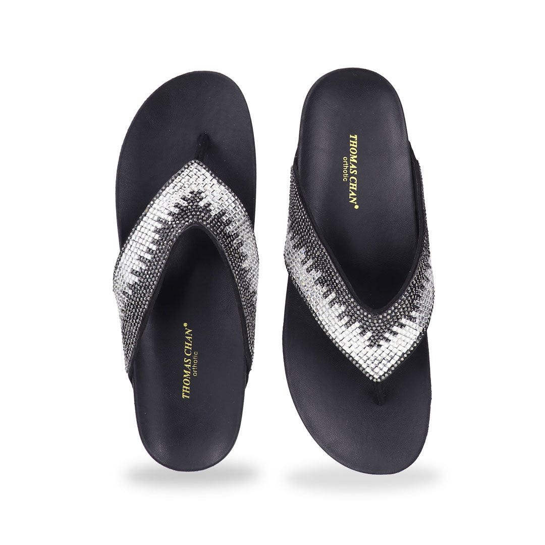 Studio shot of black suede rhinestone flip-flops showing the full front design with sparkling rhinestone straps and smooth cushioned sole.
