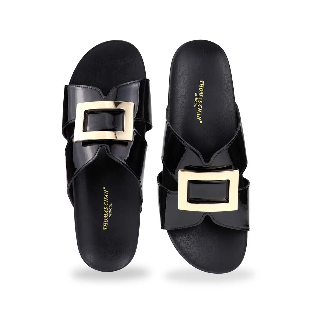Front view of Thomas Chan LiteStep flatform sandals in black patent leather, showcasing square gold buckle, on white studio background.