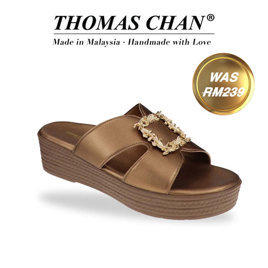 Diagonal studio view of Thomas Chan Vintage Frame Flatform Sandals in bronze with vintage-style buckle strap. The 'THOMAS CHAN®' brand is prominently displayed with the inscription 'Made in Malaysia · Handmade with Love' beneath.