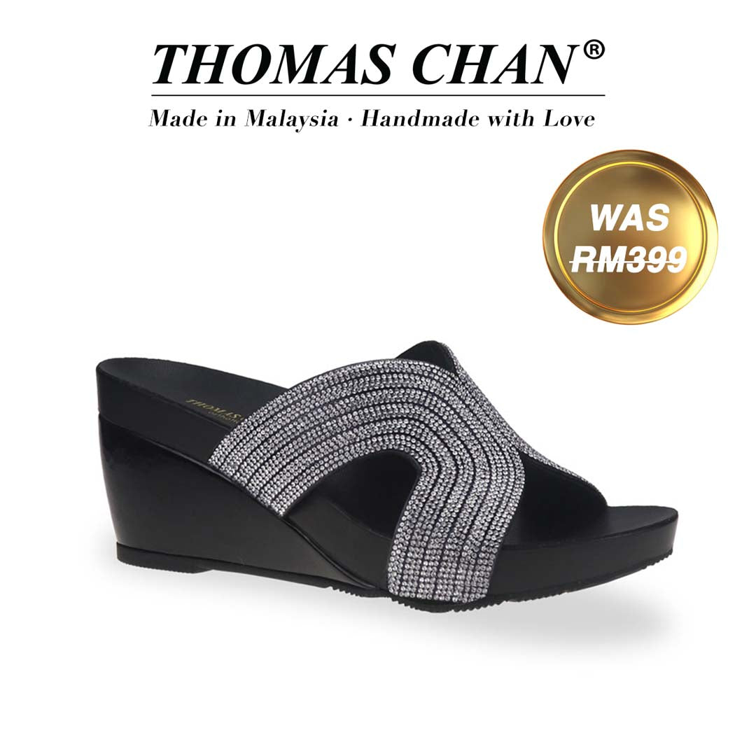 Thomas Chan's Glow Diamond Detail Wedges in black suede showcase rhinestone decorations and a 3-inch wedge heel. Designed with built-in arch-support footbed technology for enduring comfort, these wedges are as stylish as they are supportive. A gold badge proudly displays the original price of RM 399, complemented by text celebrating "THOMAS CHAN® Made in Malaysia · Handmade with Love."