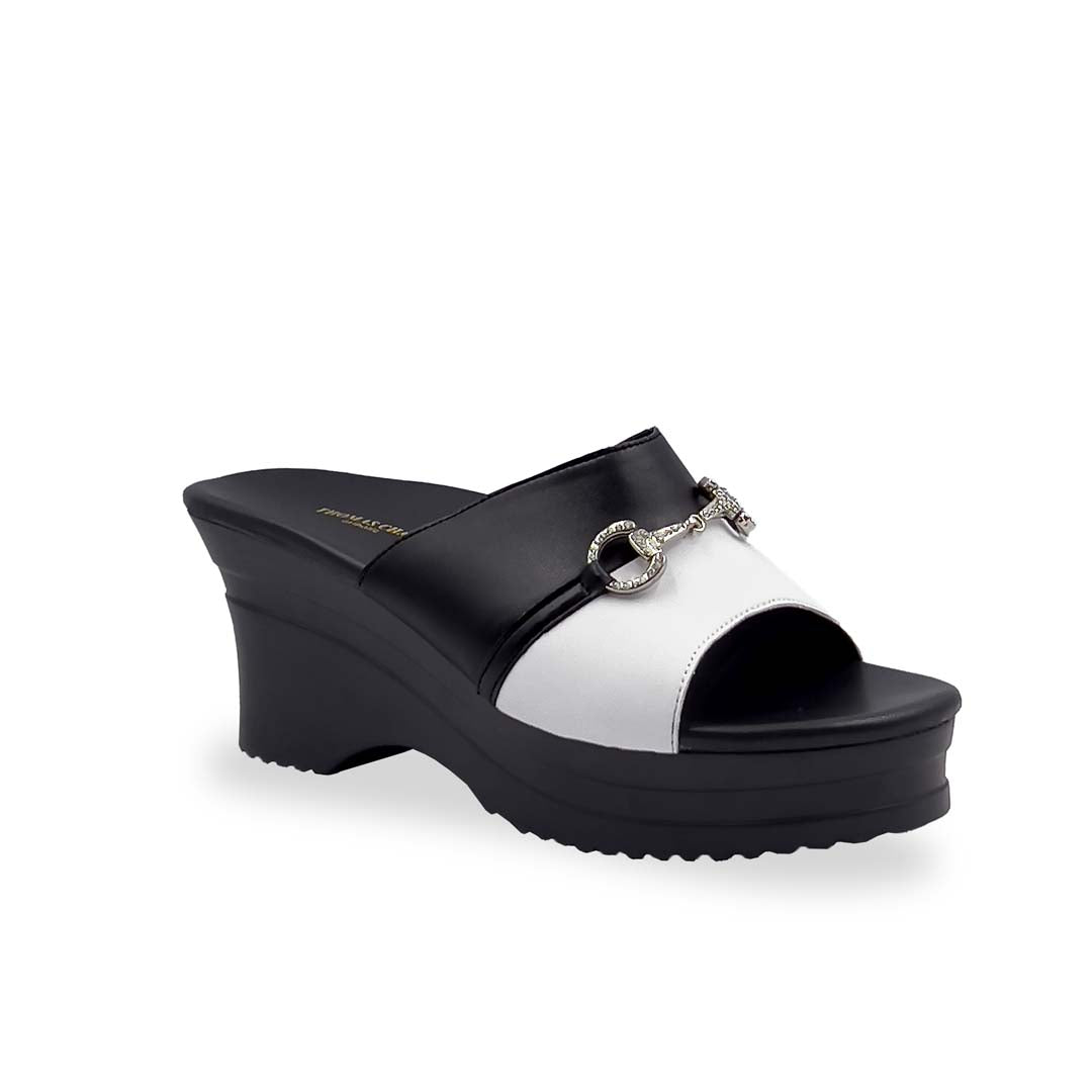 Diagonal view of Thomas Chan Two-Tone Horsebit Buckle Wedge Heels  from Cushioned Heel Series, featuring a black and white upper with a silver horsebit buckle accent, set on a beige cushioned platform sole. 