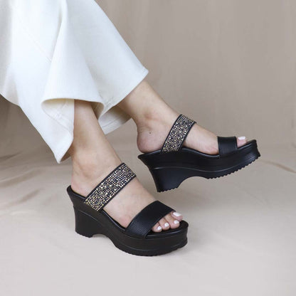 Model showcasing Thomas Chan's Strappy Rhinestone Cushioned Heels in black. The heels feature a built-in cushioned footbed, a sleek front stripe, and a dazzling rhinestone strap at the back. Set against a cream-colored backdrop, the image highlights the elegance and support of the design.