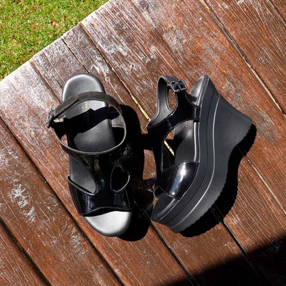 The heels displayed on a wooden floor in an outdoor pavilion, illuminated by natural light, highlighting their elegant contrast against the rustic texture.