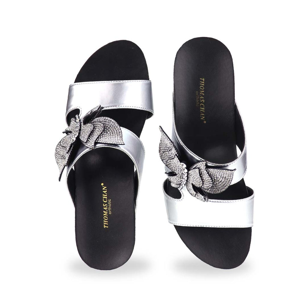 Front angle of Thomas Chan’s Glimmer Butterfly Dinner Wedges in studio lighting, focusing on the open-toe cut and intricate rhinestone butterfly centerpiece.