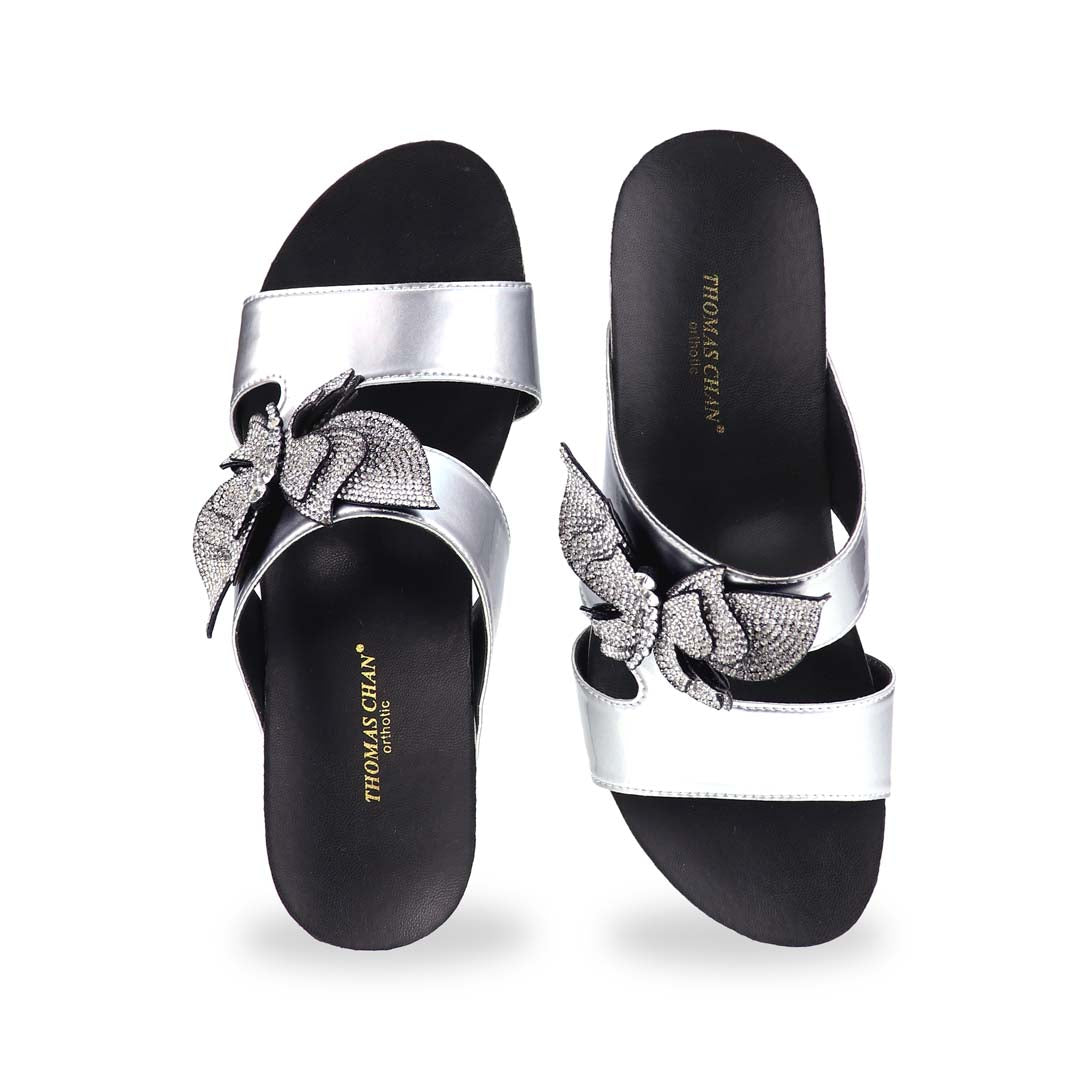Front angle of Thomas Chan’s Glimmer Butterfly Dinner Wedges in studio lighting, focusing on the open-toe cut and intricate rhinestone butterfly centerpiece.
