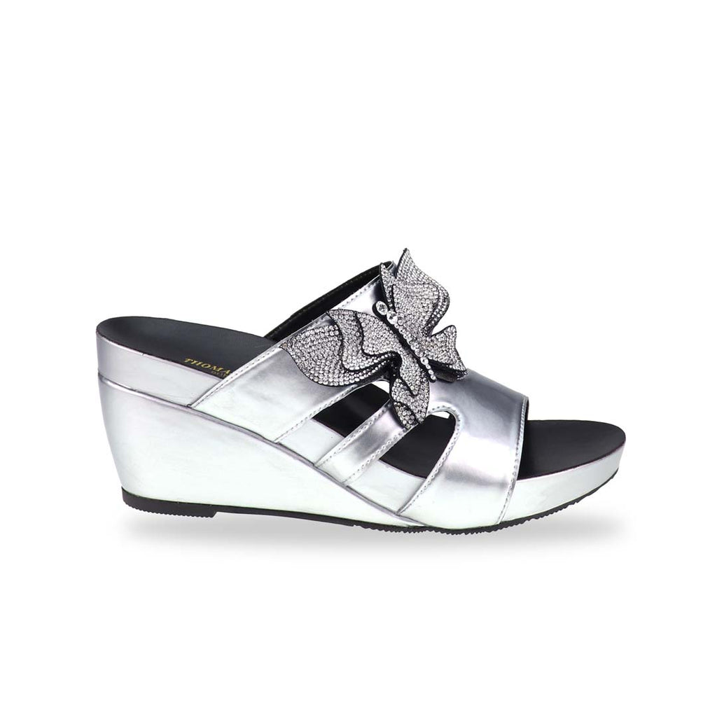 Side profile of Thomas Chan’s Glimmer Butterfly Dinner Wedges in a studio setting, highlighting the sleek metallic silver body, cut-out design, and shimmering butterfly embellishment.