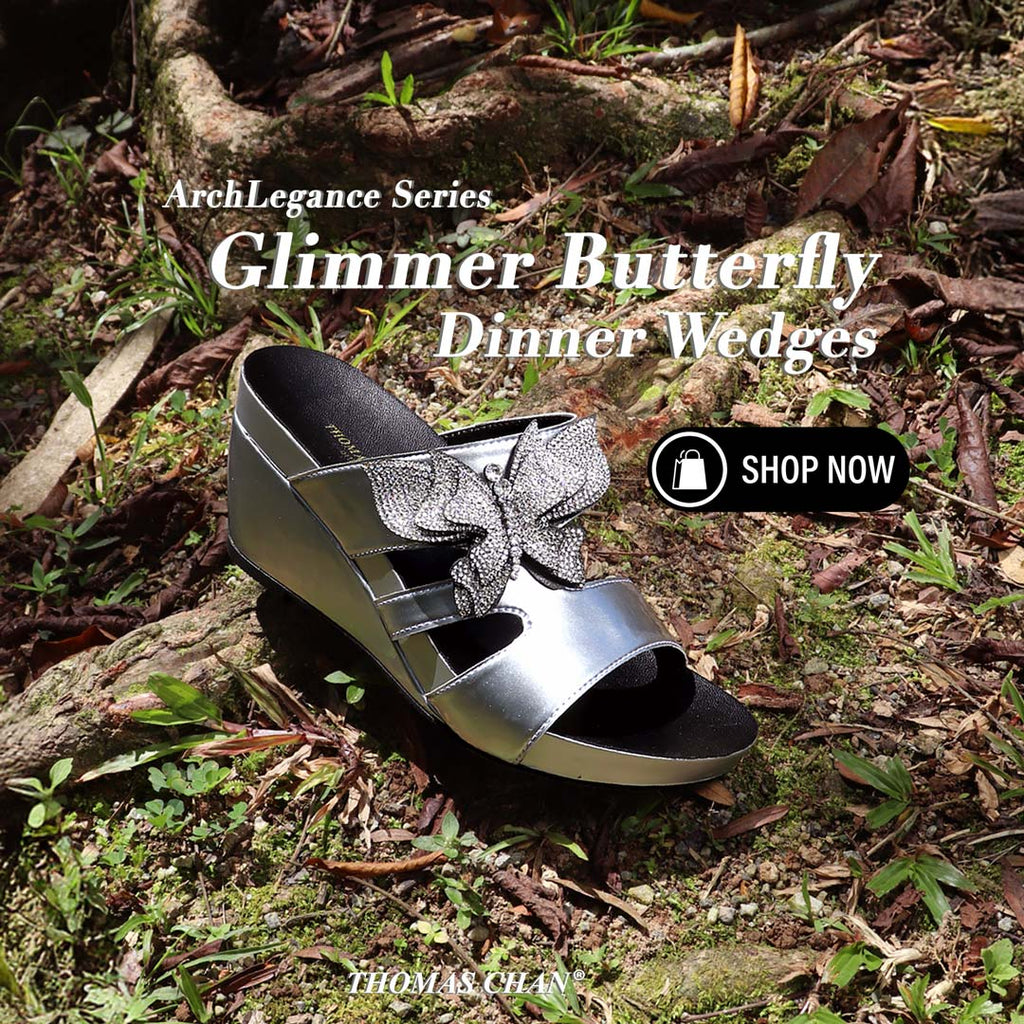 Thomas Chan’s Glimmer Butterfly Dinner Wedges in metallic silver, featuring a sparkling rhinestone butterfly design and 3-inch wedge heel, displayed outdoors on forest floor with text overlay "ArchLegance Series – Glimmer Butterfly Dinner Wedges" and a "Shop Now" button.