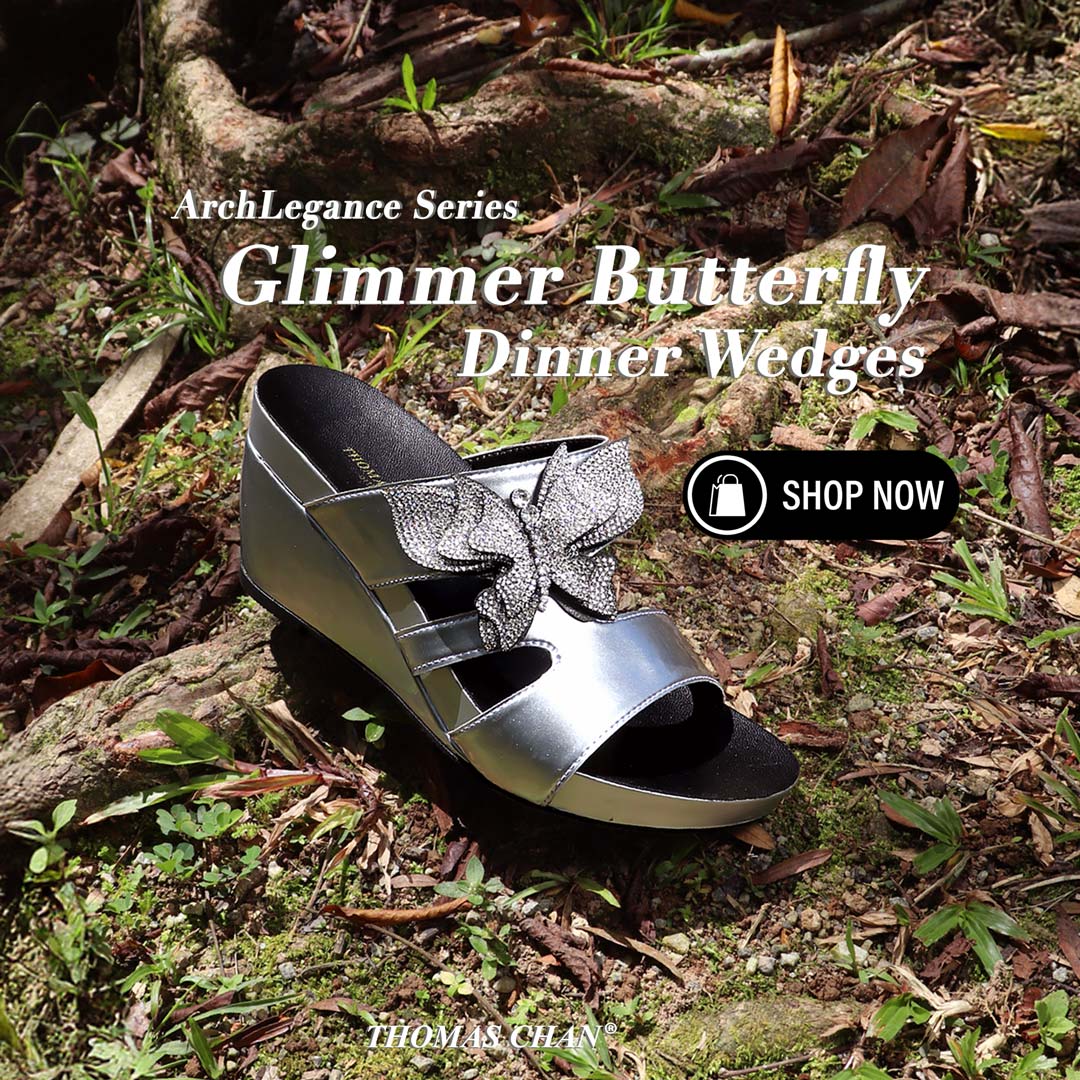 Thomas Chan’s Glimmer Butterfly Dinner Wedges in metallic silver, featuring a sparkling rhinestone butterfly design and 3-inch wedge heel, displayed outdoors on forest floor with text overlay "ArchLegance Series – Glimmer Butterfly Dinner Wedges" and a "Shop Now" button.