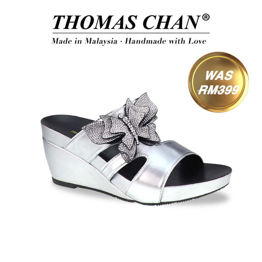 Thomas Chan’s Glimmer Butterfly Dinner Wedges in a diagonal studio view, showcasing the metallic silver finish, rhinestone butterfly detail, and 3-inch ArchLegance wedge. The Orthotic Arch-legance footbed ensures both style and comfort."THOMAS CHAN®" brand displayed with "Made in Malaysia · Handmade with Love" below. Gold and white banner highlights special offer: "Was RM399".
