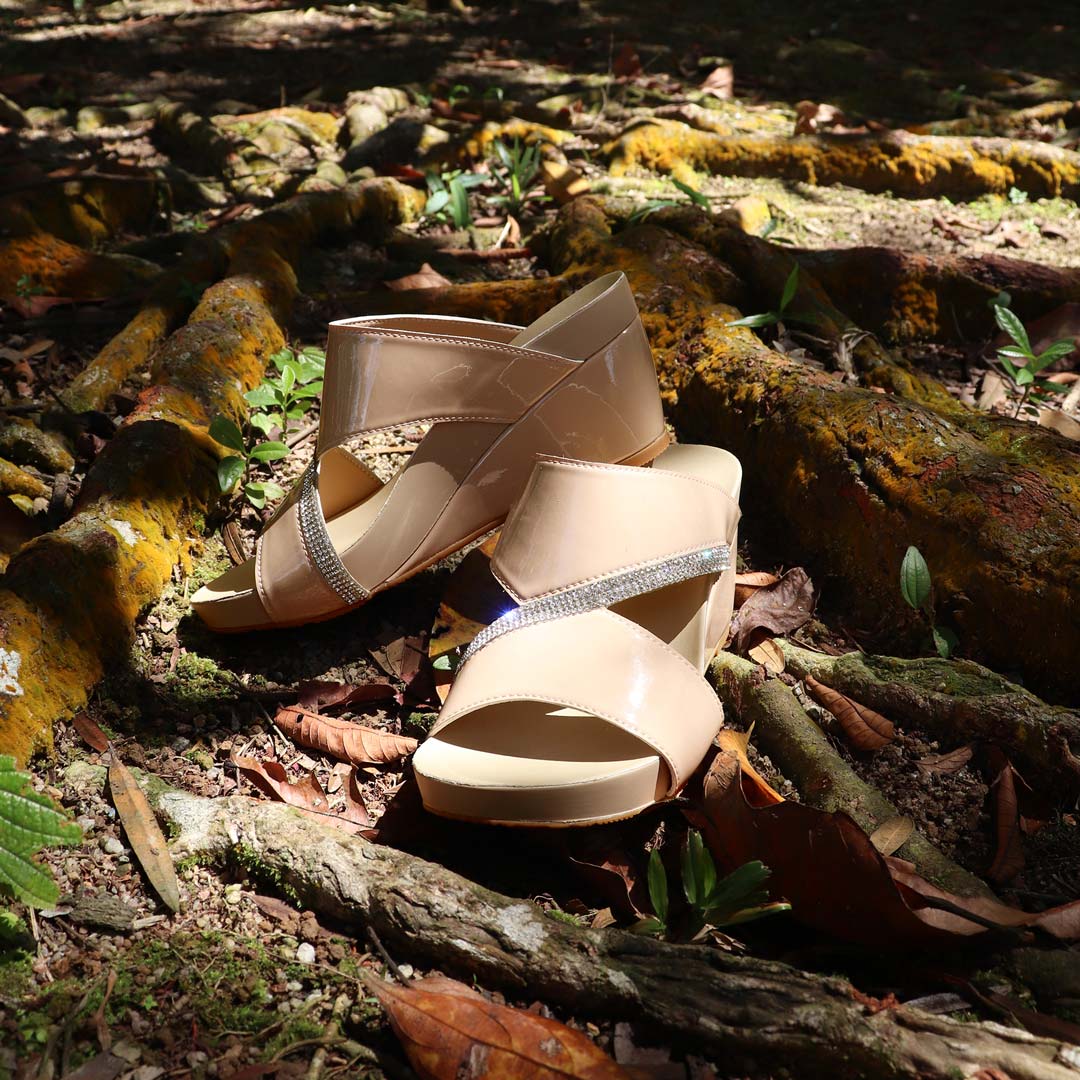 The wedges displayed on a bed of yellow mossy tree roots, blending nature with luxury. The shimmering straps catch the sunlight, creating a dreamy, ethereal aesthetic perfect for special occasions.