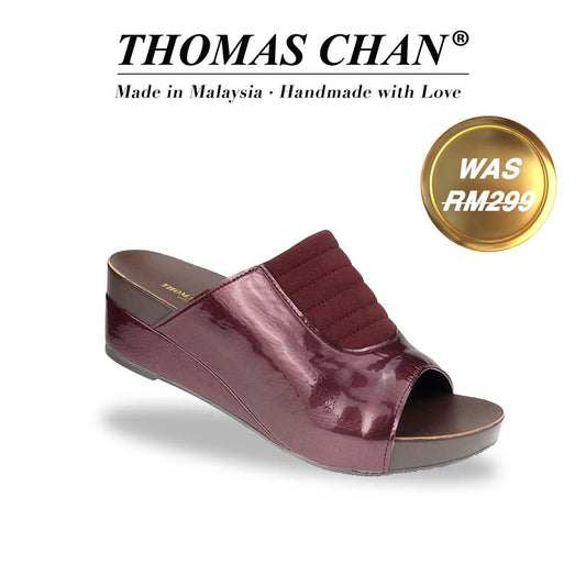 Diagonal view of Thomas Chan's Matte Cushioned Low Wedge Sandals in maroon, showcasing matte leather front padding, pattern leather accents, and the signature arch-support footbed for all-day comfort and style. "THOMAS CHAN®" brand displayed with "Made in Malaysia · Handmade with Love" below. Gold and white banner highlights special offer: "Was RM299."