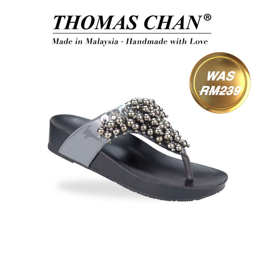 Diagonal view of Thomas Chan's Pearl Tassel Flip-Flops from the LiteStep Collection. The sandals feature a glossy grey strap adorned with pearl tassel embellishments, paired with a comfortable flatform sole. The 'THOMAS CHAN®' brand is displayed below with 'Made in Malaysia · Handmade with Love.' A gold and white banner highlights a special offer: 'Was RM239'
