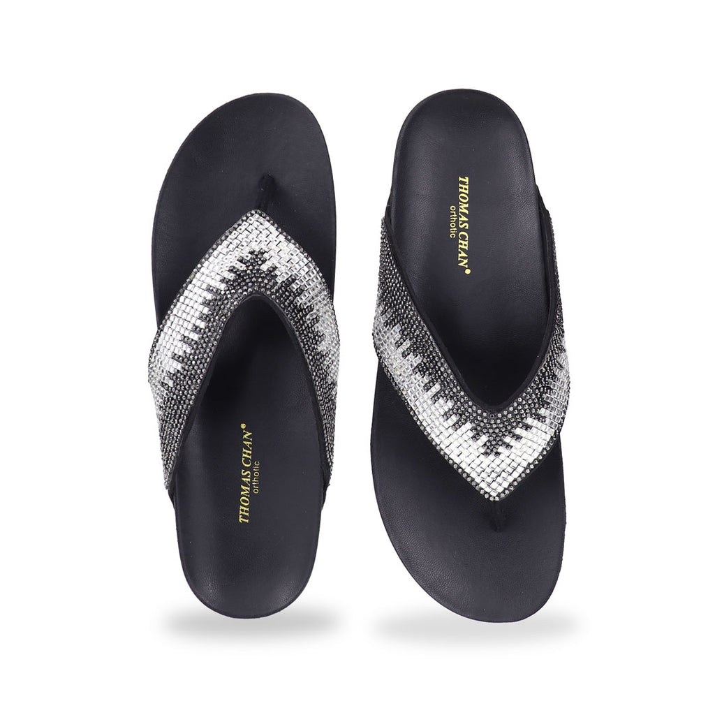 Studio shot of black suede rhinestone flip-flops showing the full front design with sparkling rhinestone straps and smooth cushioned sole.