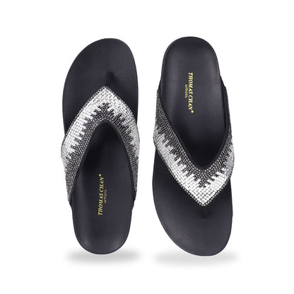 Studio shot of black suede rhinestone flip-flops showing the full front design with sparkling rhinestone straps and smooth cushioned sole.