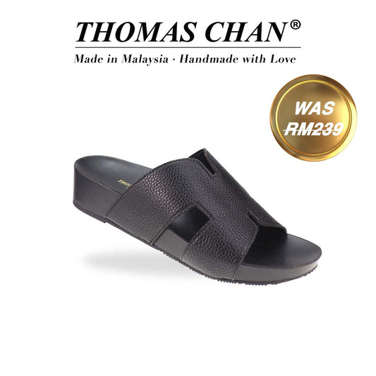 A stylish angle of the H-Strap Pebble Lychee Flatform Sandals in black, highlighting the textured material and smooth, cushioned footbed for all-day comfort. The top of the image displays the brand name "THOMAS CHAN®" with the text "Made in Malaysia · Handmade with Love" below it. There is a gold and white banner on the right side that says "Was RM239".