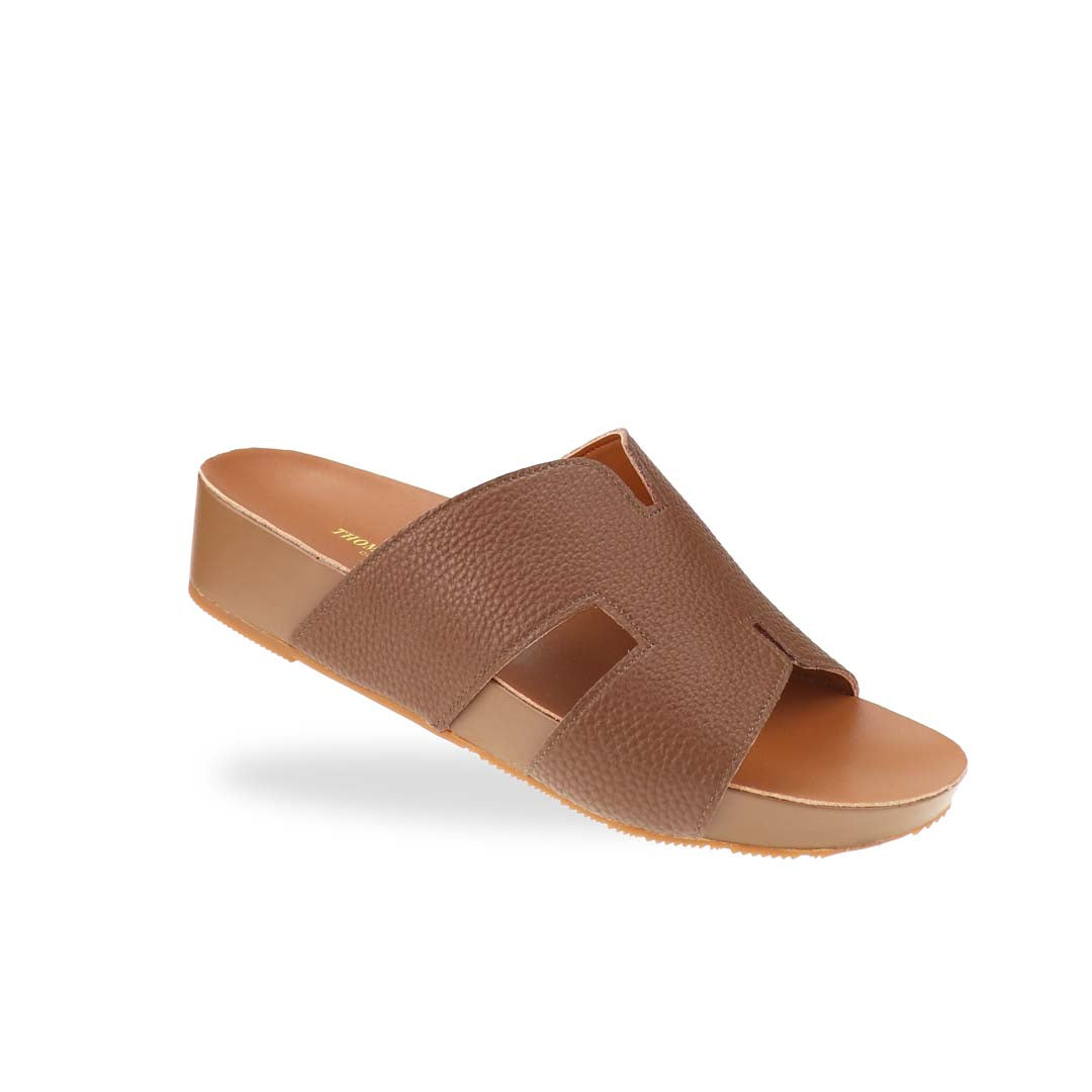 A stylish angle of the H-Strap Pebble Lychee Flatform Sandals in brown, highlighting the textured material and smooth, cushioned footbed for all-day comfort.