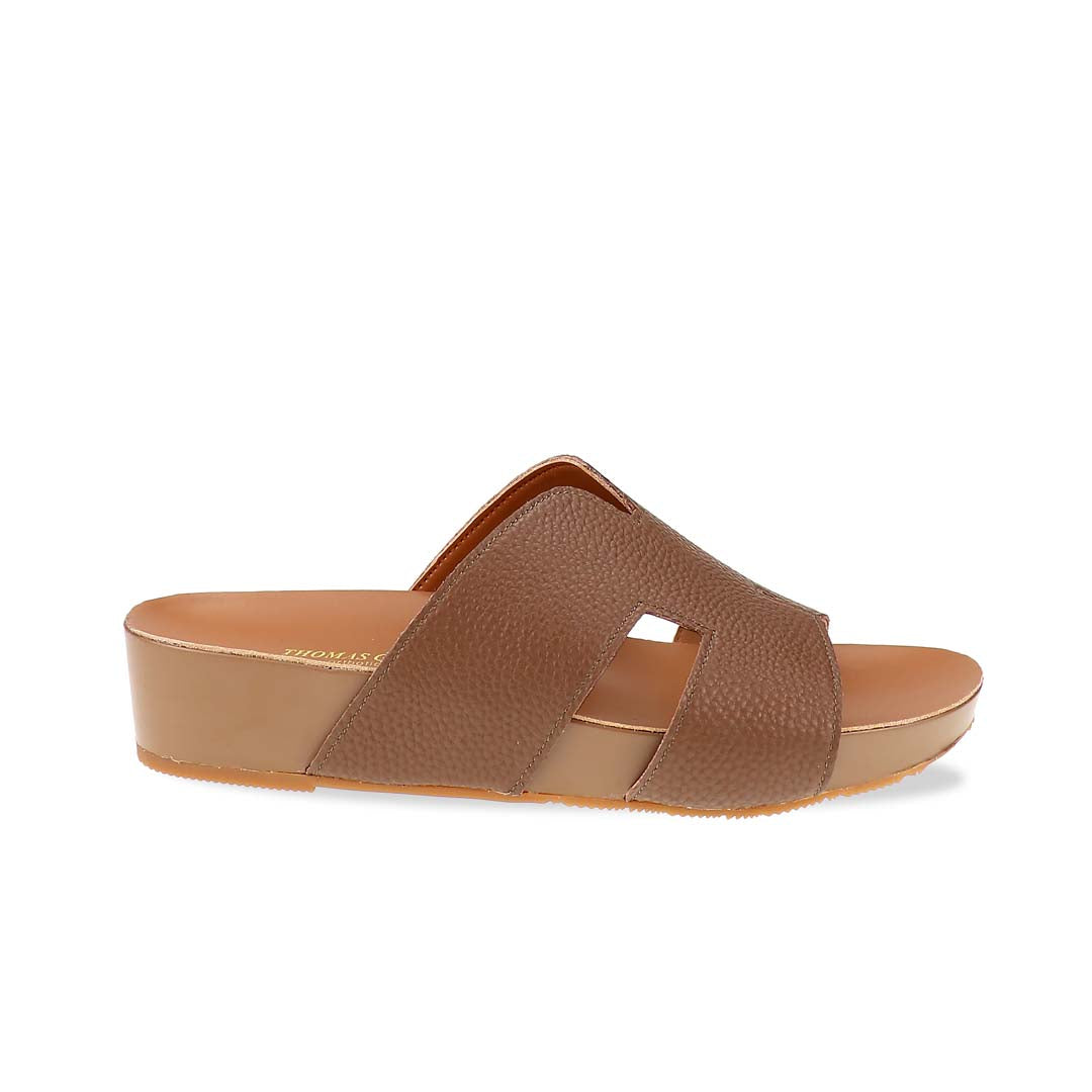 A sleek pair of Thomas Chan's H-Strap Pebble Lychee Flatform Sandals in black displayed in a studio setting, showcasing the pebble lychee-textured H-strap and lightweight flatform sole.