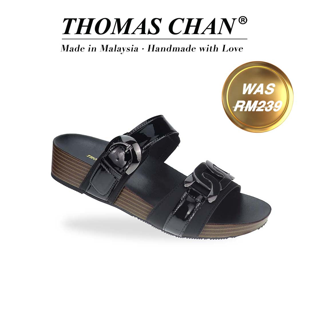 Diagonal view of Thomas Chan’s Metallic Duo-Strap Adjustable Sandals in black, showcasing sleek metallic straps, an adjustable buckle for a perfect fit, and a LiteStep flatform footbed for added comfort. The 'THOMAS CHAN®' brand logo is prominently displayed, with the inscription 'Made in Malaysia · Handmade with Love' beneath it. A gold and white banner highlights the special offer: 'Was RM239.'