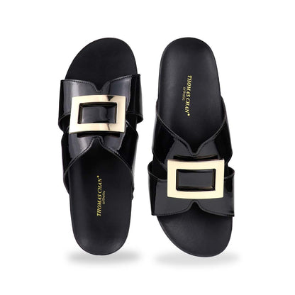 Front view of Thomas Chan LiteStep flatform sandals in black patent leather, showcasing square gold buckle, on white studio background.