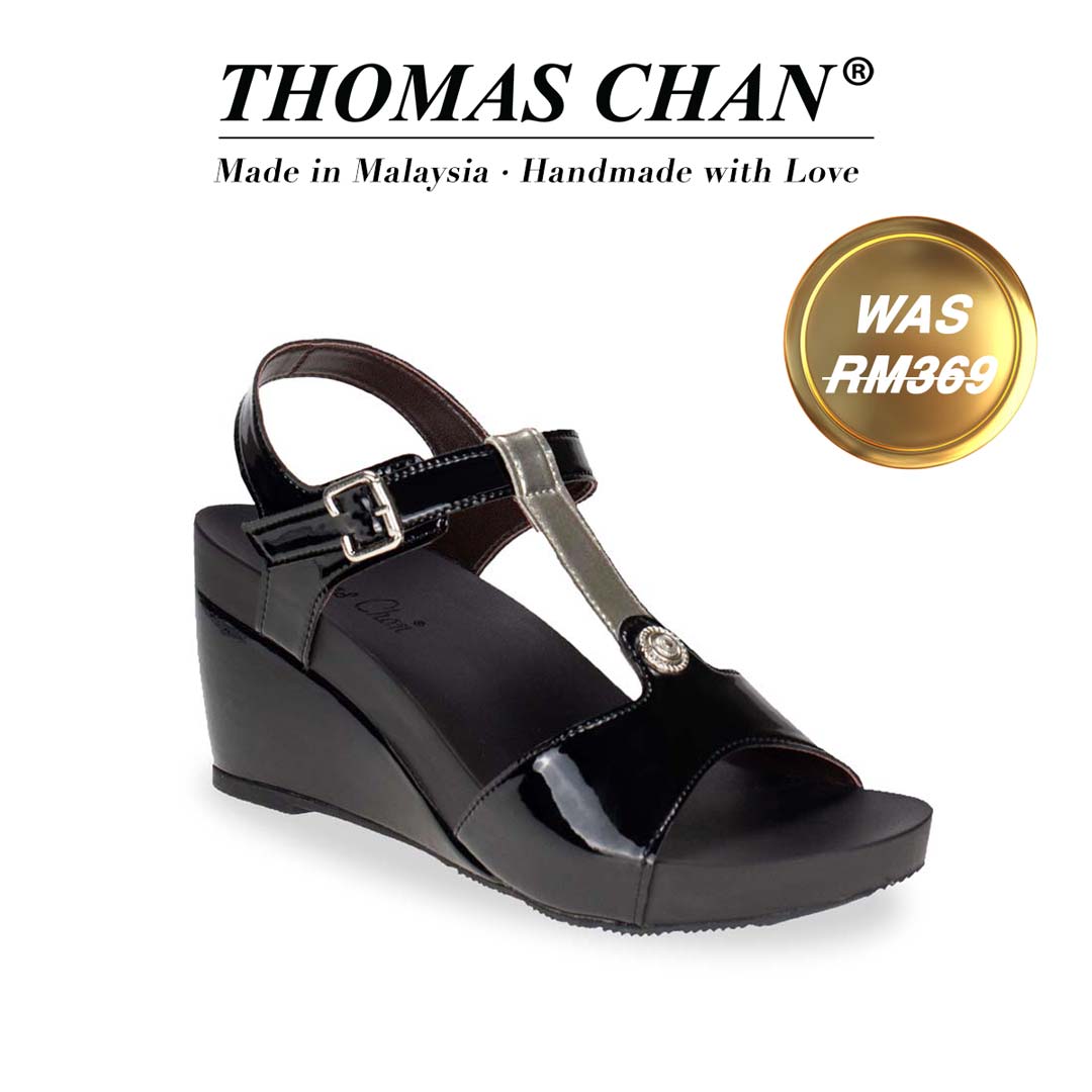 Thomas Chan T-Strap Slingback Wedges in black & silver, combining style and comfort. The sandal showcases a T-strap design embellished with metallic studs and a 3-inch wedge heel. Designed with built-in arch-support footbed technology for enduring comfort. A gold badge displays the original price of RM369, with accompanying text above celebrating "THOMAS CHAN® Made in Malaysia · Handmade with Love."