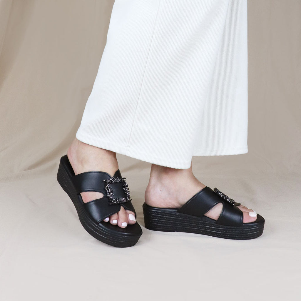 Model wearing Thomas Chan Vintage Frame Flatform Sandals in black from the Cushioned Footbed collection, styled casually in an outdoor setting.