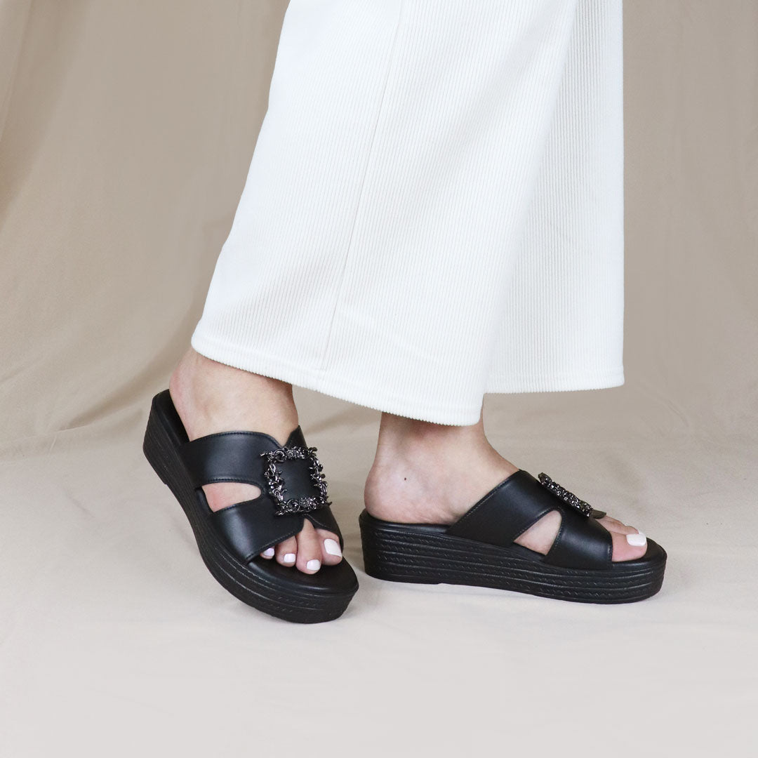 Model wearing Thomas Chan Vintage Frame Flatform Sandals in black from the Cushioned Footbed collection, styled casually in an outdoor setting.