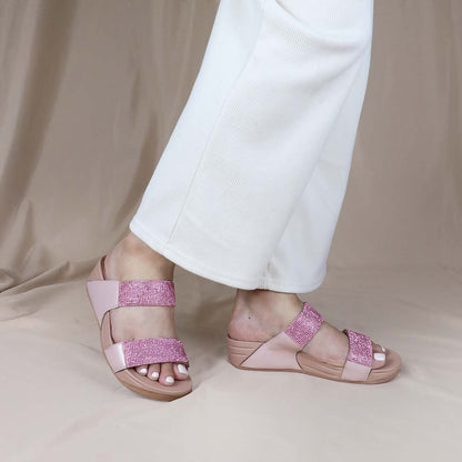 A model standing while wearing the Diamond Embellished Duo-Strap Bounce Care Sandals in Nude Pink, effortlessly showcasing their stylish yet comfortable design. The soft rubber sole and sparkling embellishments enhance the outfit, blending comfort with elegance.