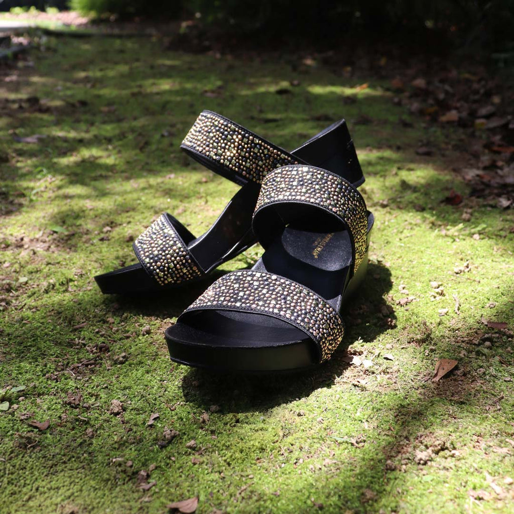 Blinkies Twin Band Wedges by Thomas Chan – rhinestone low wedge sandals for women in black, photographed in natural sunlight on mossy garden ground.
