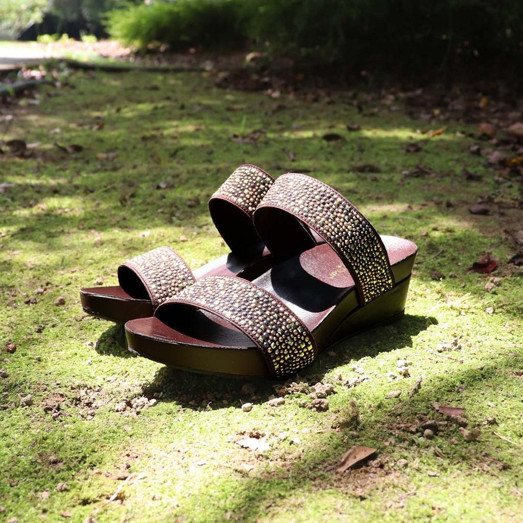 Blinkies Twin Band Wedges by Thomas Chan – rhinestone low wedge sandals for women in brown, photographed in natural sunlight on mossy garden ground.