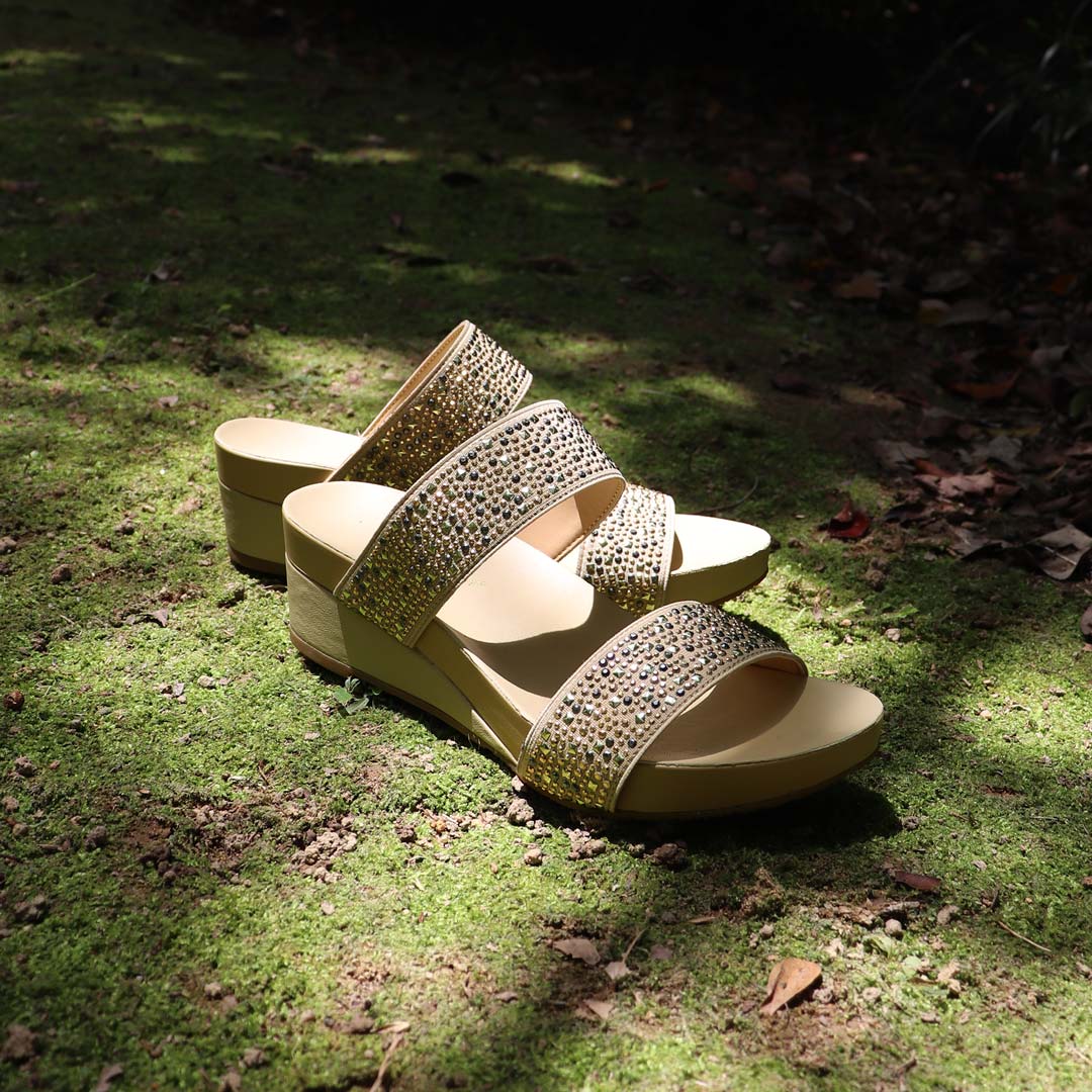 Blinkies Twin Band Wedges by Thomas Chan – rhinestone low wedge sandals for women in cream, photographed in natural sunlight on mossy garden ground.
