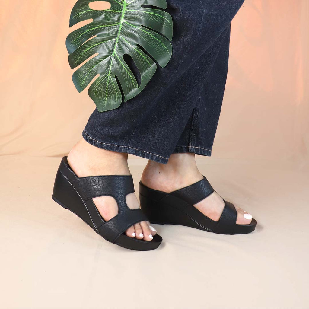 Model wearing Thomas Chan Simplicité High Wedges indoors — matte black minimalist wedge sandals with 3-inch heel and orthotic arch support, styled for everyday chic.