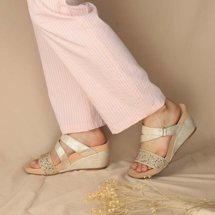 shiny light gold colour wedge sandals in strappy designs paired with warm tone ankle pants